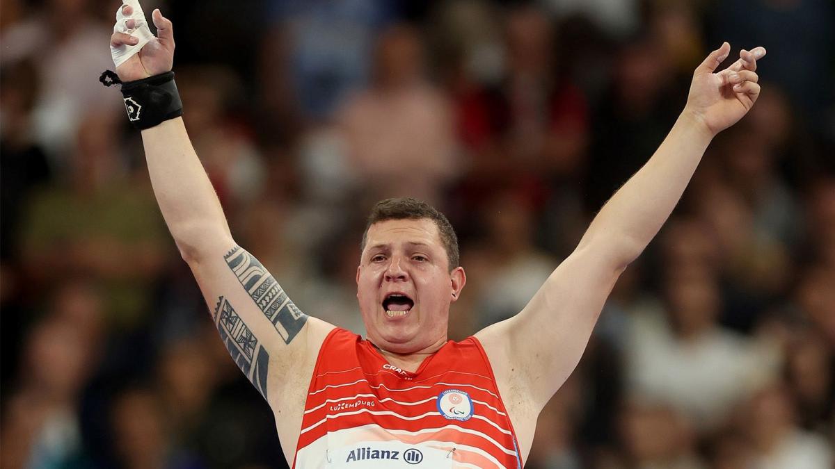 A male athlete opens his arms widely to celebrate