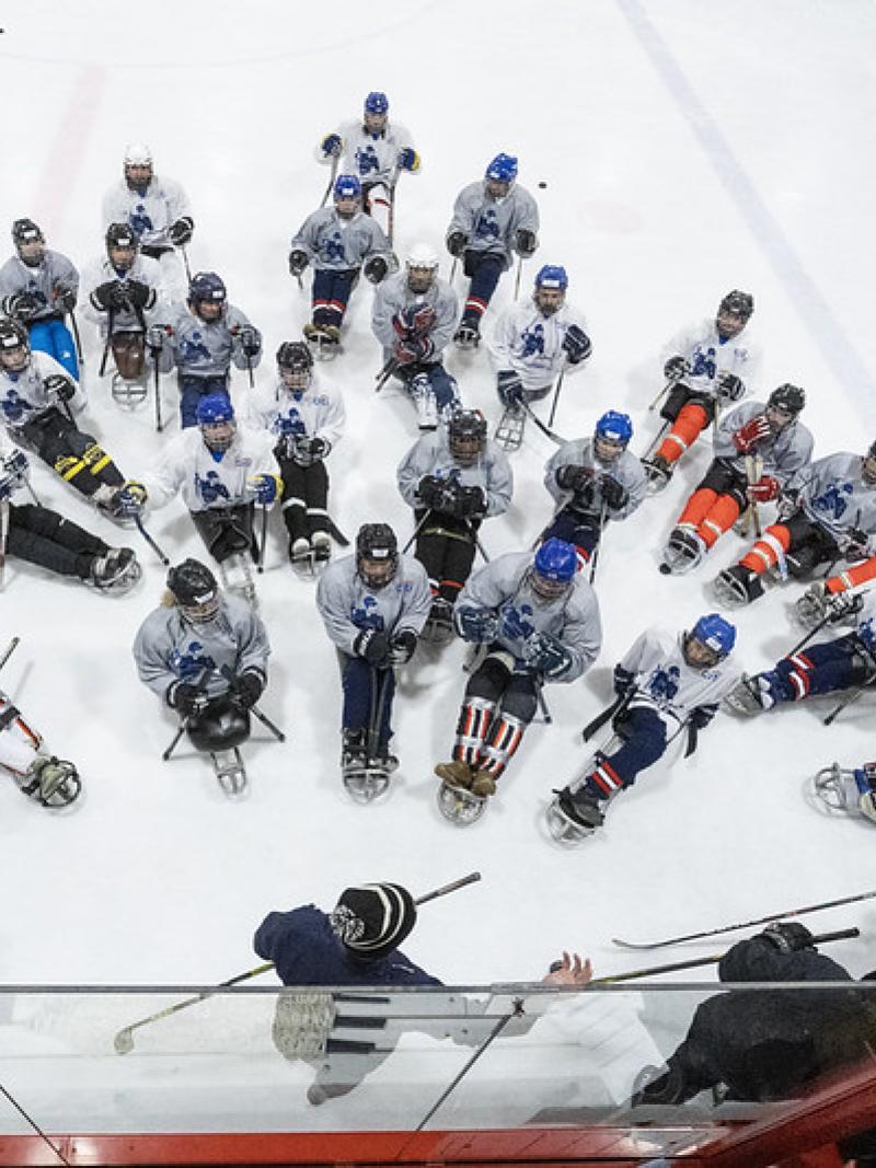 A group of Para ice hockey players receiving instructions during a camp