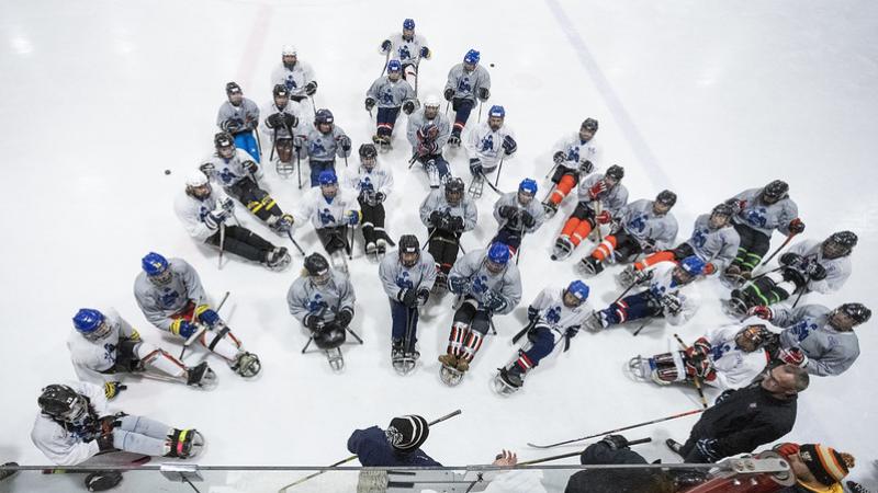 A group of Para ice hockey players receiving instructions during a camp