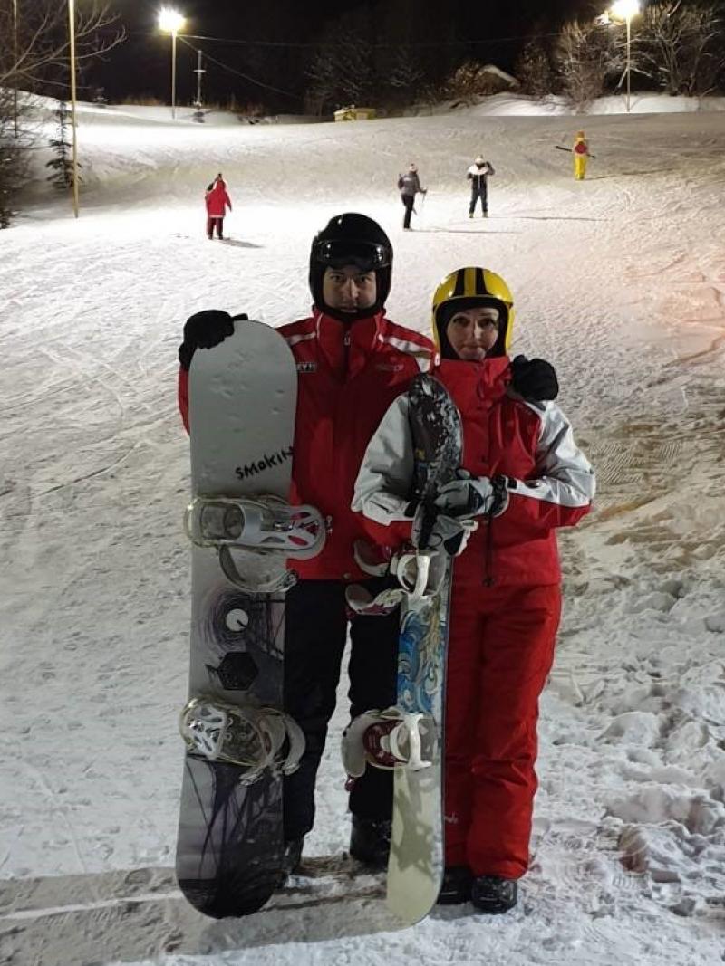 A man and a woman with snowboard gear standing in a snowy slope