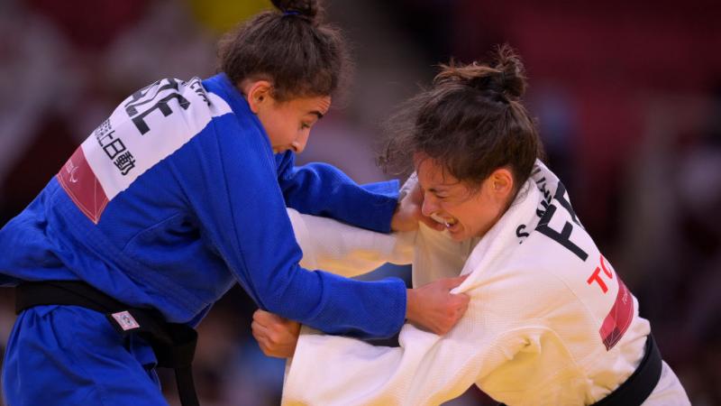 Two woman competing in Para judo grab each other by the arms