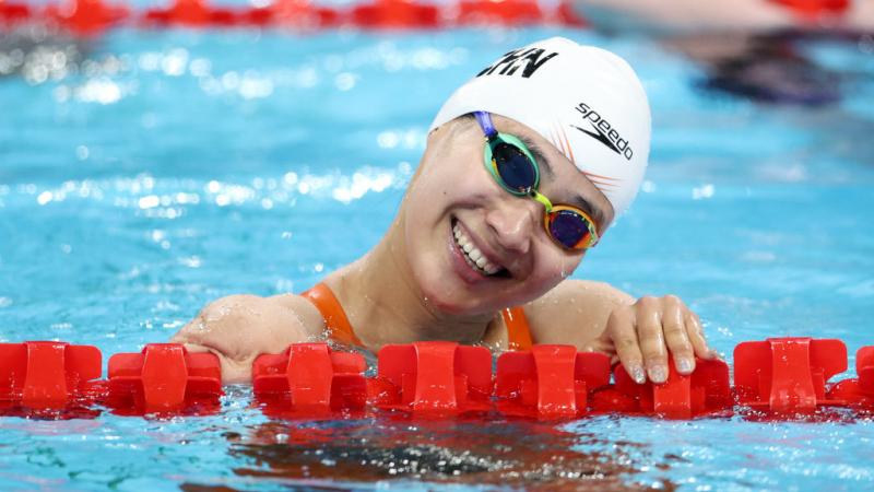 A female swimmer smiling from the pool