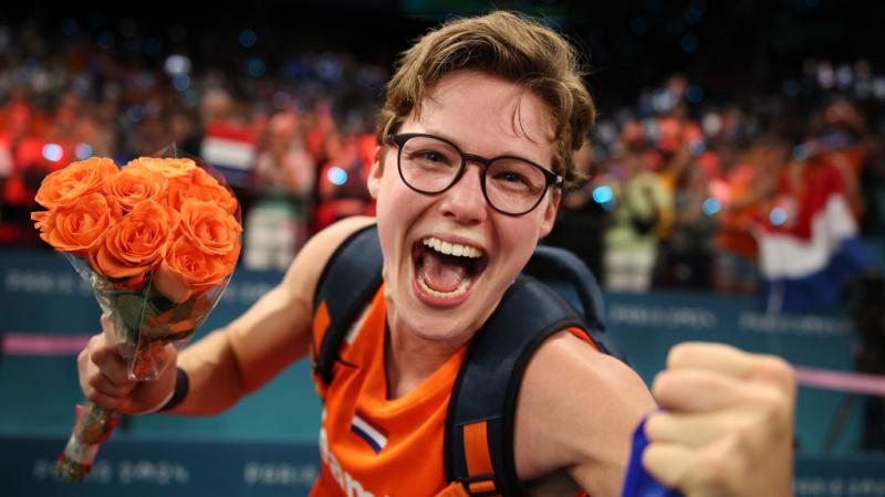 Bo Kramer celebrates into the camera while holding orange flowers