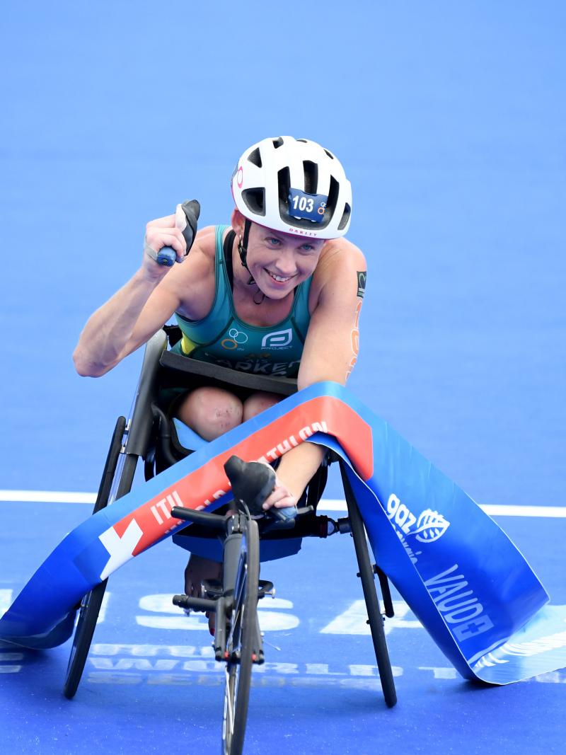 Woman in racing chair crosses finish line tape