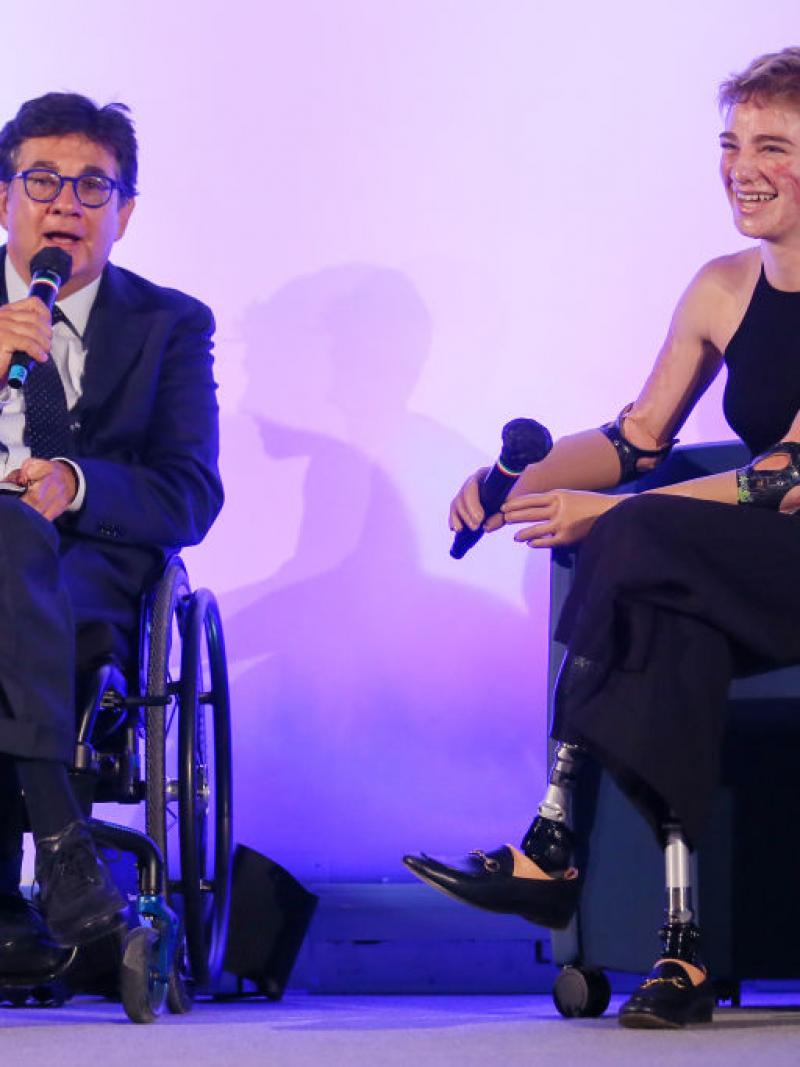 A male official and a female Paralympic athlete are speaking during a conference.