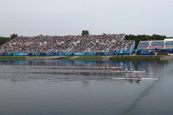 A general view of the Para rowing stadium. There are many fans in the stands watching a Para rowing race.
