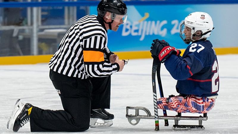 A Para ice hockey official and a player talking in an ice rink