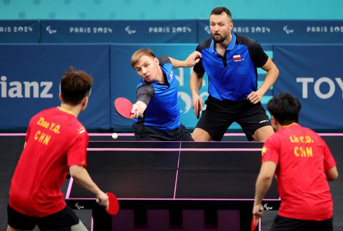 Athletes compete in a men's doubles match