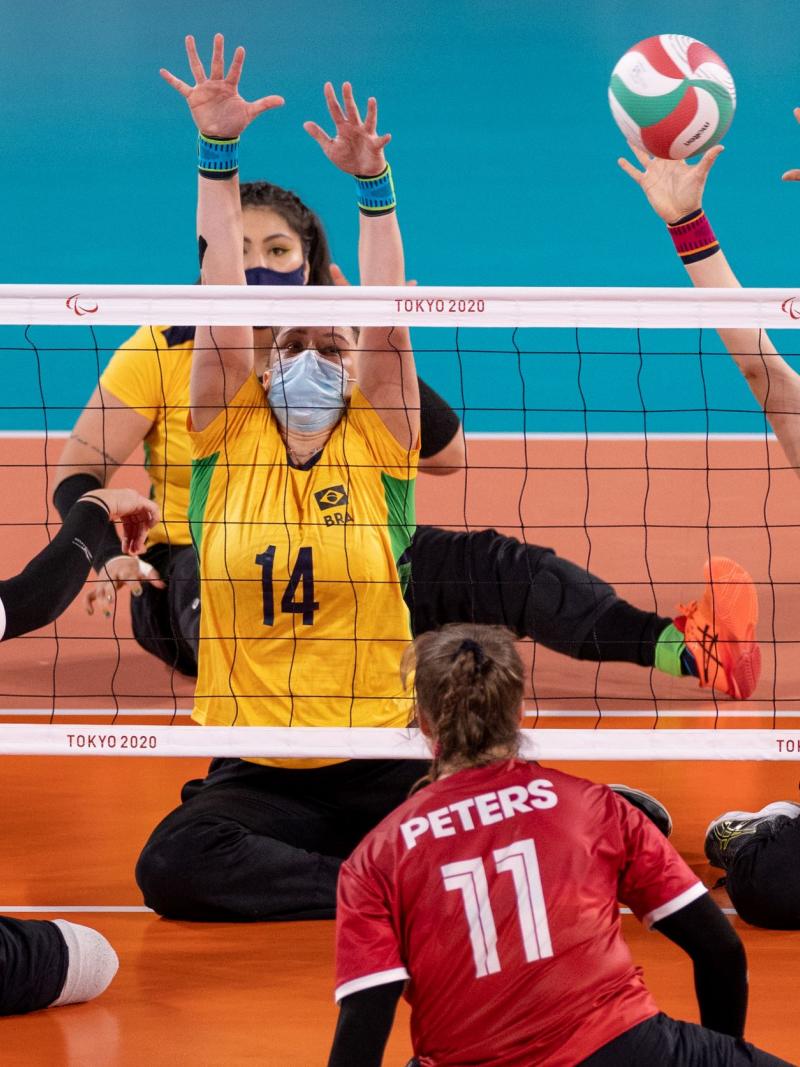 A female sitting volleyball player from Brazil plays the ball during a match against Canada.