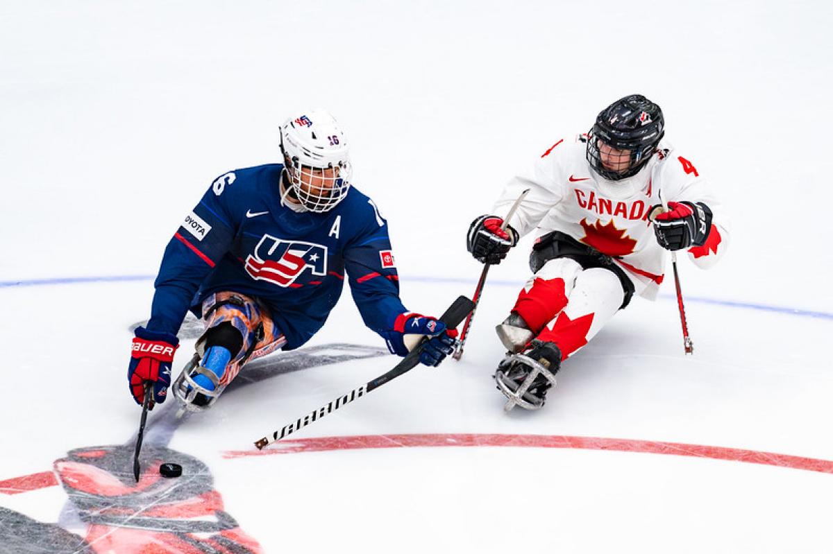 Two Para ice hockey players from USA and Canada in a game