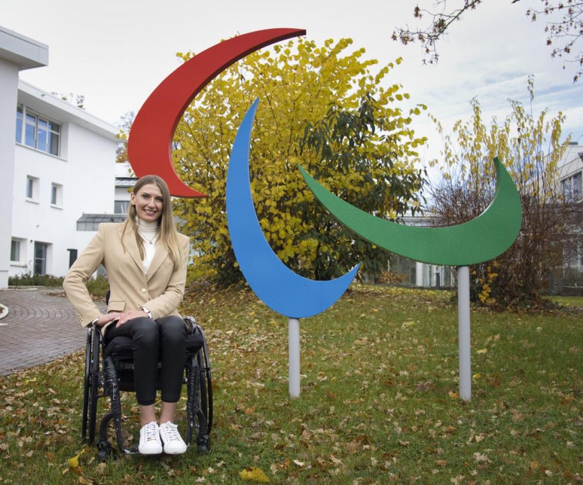 Vladyslava Kravchenko poses for a photograph next to the Paralympic symbol in front of the IPC headquarters in Bonn, Germany