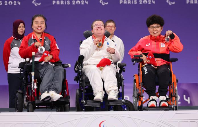 Three boccia athletes - Aurelie Aubert of Team France (C), Silver medalist Yee Ting Jeralyn Tan of Team Singapore (L) and Bronze medalist Hiromi Endo of Team Japan (R) - are holding their medals on a white podium