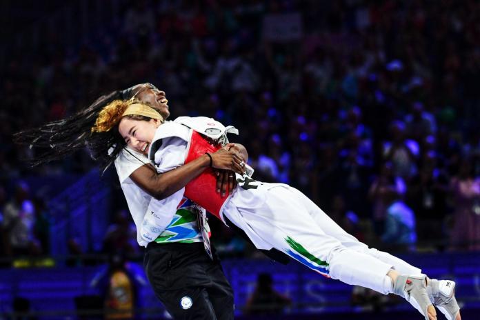 Coach Haby Niare lifts up Zakia Khudadadi, a female Para taekwondo athlete, to celebrate