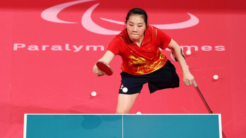 A female Para table tennis player competes using a cane